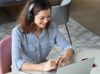 A woman sitting in front of her laptop wearing headphones